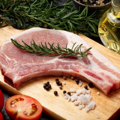 raw pork chop steak on the dark wooden background.